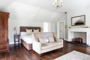BallynahinchMillbrook Lodge的一间卧室配有一张床、一把椅子和一个壁炉