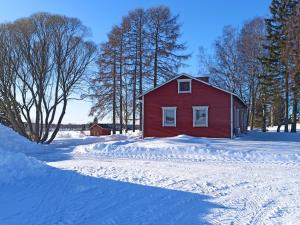 伊萨尔米Laukkumäki farm的雪地里的一个红谷仓,有树木