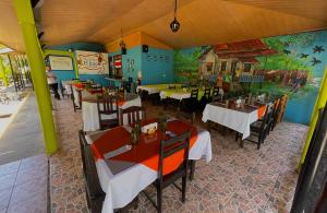 托尔图格罗Hotel El Icaco Tortuguero的餐厅设有桌椅,墙上挂有绘画作品