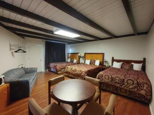 克兰布鲁克库特尼乡村酒店的客房设有两张床、一张桌子和一张沙发。