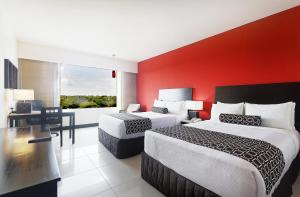 比亚埃尔莫萨比亚埃尔莫萨皇冠假日酒店的酒店客房设有两张床和红色的墙壁。
