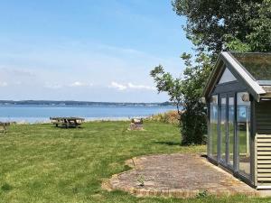 布罗艾厄6 person holiday home in Broager的一个小棚子,有野餐桌和湖泊