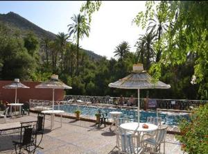 伊莫泽德斯伊达欧塔纳尼Maison d'hôtes tifrit-Paradise valley的游泳池配有桌子和遮阳伞,周围的人坐在游泳池周围