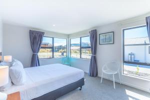 特卡波湖Neptune - Lake Tekapo的一间卧室设有床、两扇窗户和一把椅子