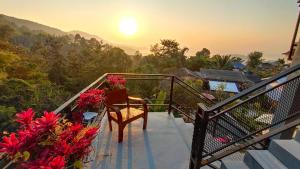 清莱บ้านภูคำฟ้า ดอยปู่ไข่ Baan Phu Kham Fah的阳台配有椅子和鲜花