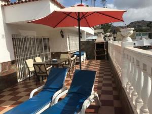 波多黎各Bungalow Isla Margarita的阳台的天井配有椅子和遮阳伞。
