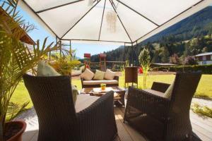 萨尔巴赫Hotel Austria - inklusive Joker Card im Sommer的庭院配有两把椅子、一张沙发和一把遮阳伞。