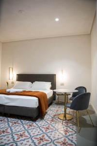卡塔尼亚20 Miglia Boutique Hotel的卧室配有1张床、1张桌子和1把椅子