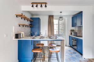 圣马洛Le Cap Cézembre - Intra-Muros Saint-Malo的厨房配有蓝色橱柜和酒吧凳子