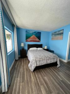 英格尔伍德LA Adventurer Hotel的一间卧室配有一张蓝色墙壁和木地板的床。