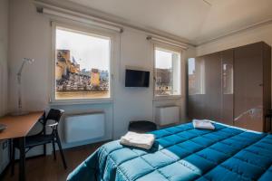 佛罗伦萨Residenza Benizzi rooms in the heart of Florence的一间卧室配有蓝色的床、一张书桌和窗户。