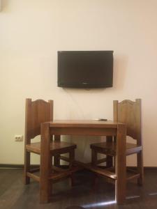 乌日霍罗德Lux na Osipenko的一张木桌,配有两把椅子和墙上的一台电视