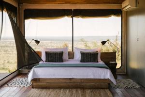 温特和克Our Habitas Namibia的一张位于带大窗户的房间内的床铺