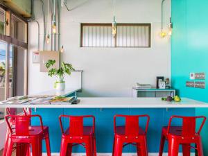 北谷町海墙旅舍的厨房配有红色椅子和蓝色柜台