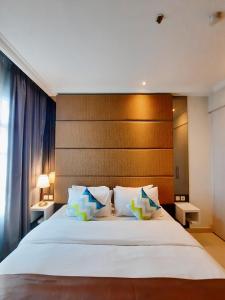 雅加达The Bellezza Hotel Suites的卧室配有一张白色大床和木制床头板