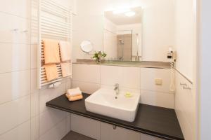 瓦尔德克PlusNaturHotel direkt am Ederseeufer Waldhotel Wiesemann und Ferienapartments的白色的浴室设有水槽和镜子