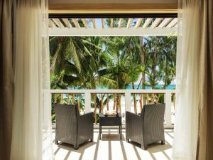 长滩岛卡米拉海滩度假村别墅的一个带椅子和棕榈树的门廊的房间