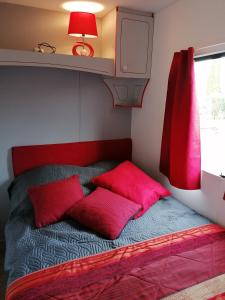 CampignyLe pré vert的小房间一张带红色枕头的床