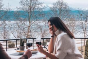 约阿尼纳Akti Hotel Ioannina的坐在桌子旁的女人,拿着两杯酒