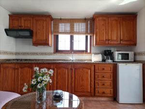 丰卡连特德拉帕尔马El Somadero B的厨房配有木制橱柜和鲜花桌