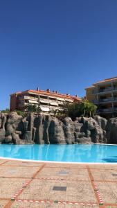 拉克鲁斯Piso Jardines del Teide en el Puerto de la Cruz的大楼前的蓝色海水游泳池
