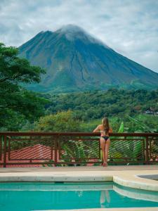 福尔图纳Miradas Arenal Hotel & Hotsprings的坐在围栏上,坐在比基尼的女人俯瞰山脉