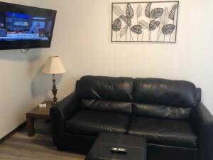 奥沙克湖Rockwood Resort Motel的客厅设有一张黑色皮沙发,配有平面电视。