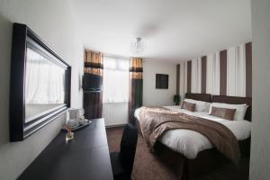 格拉斯哥伯恩赛德酒店的一间卧室配有一张大床和电视