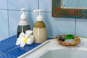 麦岛Sabai Beach Resort的两瓶肥皂和一个水槽上的一篮鲜花