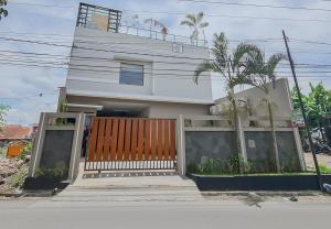 打横RedDoorz Syariah @ Boemi Guesthouse Tasikmalaya的一座白色的房子,有门和棕榈树