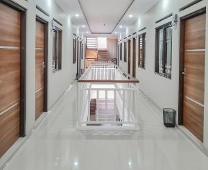 打横RedDoorz Syariah @ Boemi Guesthouse Tasikmalaya的走廊设有木门,铺有白色瓷砖地板。