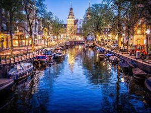 阿姆斯特丹Luxury Prinsengracht Canal House Jordan Area的夜间在城市里开通一条有船只的运河