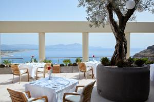 林都斯Lindos Blu Luxury Hotel-Adults only的一间设有白色桌椅和树的餐厅