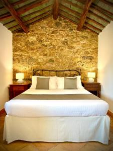 阿尔扎凯纳Punta D'Acu Country Resort的卧室配有一张白色大床和石墙