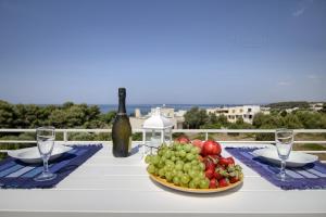 莱乌卡Jacuzzi Holiday Homes的一张桌子,上面放着一碗水果和一瓶葡萄酒