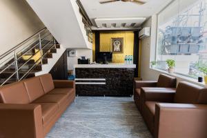 蒂鲁帕蒂Hotel Mookambika Comforts的一间设有棕色皮沙发的等候室和一间酒吧