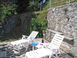 蒙特马尼奥Holiday Home Villetta degli Orti by Interhome的石墙前有三把白色椅子和一张桌子