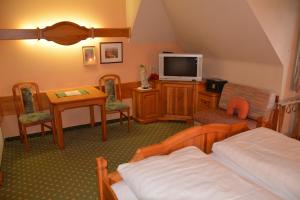 巴德瓦尔特斯多夫费舍尔餐厅酒店的一间卧室配有一张床、一台电视和一张桌子
