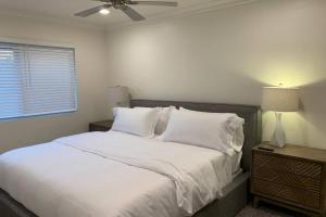 亨廷顿海滩City Center Villa - Pool, Patio & Close To Beach!的一间卧室配有一张带白色床单的床和吊扇。