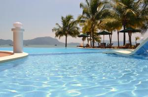 瓜埠兰卡威海洋居酒店的棕榈树度假村的游泳池和灯塔