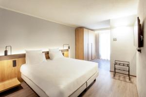 帕尔马Palazzo Le Poste - Suite and Apartments的卧室设有一张白色大床和一扇窗户。