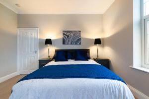威姆斯洛Modern Living 2 Bedroom Apartment South Wilmslow的一间卧室配有一张带蓝色枕头的大床