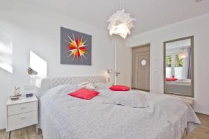 劳特尔巴赫hafennahe Ferienwohnung im Erdgeschoss mit Terrasse - Haus Hafenkieker FeWo 02的白色卧室配有一张带红色枕头的大床