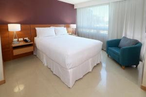 瓜达拉哈拉瓜达拉哈拉博览会驻桥套房假日酒店的卧室配有一张白色大床和一张蓝色椅子