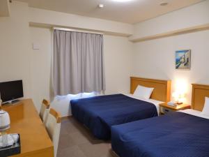 YoshidaSmile Hotel Shizuoka Yoshida Inter的酒店客房设有两张床、一张桌子和一台电视。