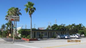 劳德代尔堡Vacation Inn Motel - Fort Lauderdale Airport的停车场内有车辆的建筑物