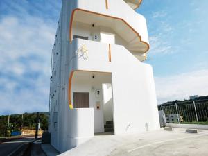 读谷村CHULAX OKINAWA YOMITAN【Designer Condominium Hotel】的白色的建筑,带有螺旋楼梯
