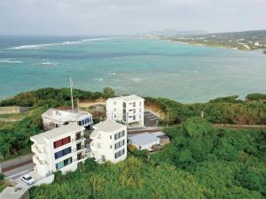 读谷村CHULAX OKINAWA YOMITAN【Designer Condominium Hotel】的两座白色建筑和海洋的空中景观