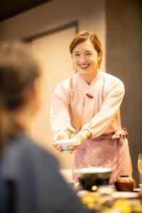 伊豆之国市小松家八之坊酒店的站在一个盘子的厨房中的女人