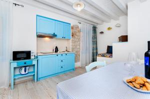 罗维尼Apartments & Rooms La casa Barbaro的厨房配有蓝色橱柜和一张带一碗面包的桌子